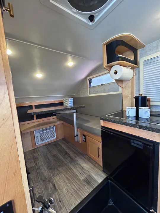 RV rental interior features a compact dinette, kitchenette with sink & fridge, plus AC. Ideal for cozy adventures.. Xtreme Outdoors Xtreme Outdoors Trailer 2022