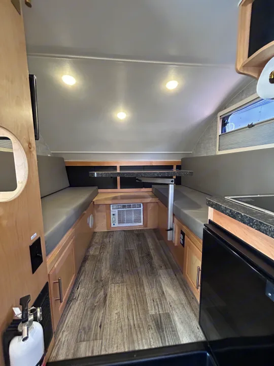 This compact RV rental or camper interior showcases a dining booth, kitchenette, AC unit, and overhead lighting.. Xtreme Outdoors Xtreme Outdoors Trailer 2022