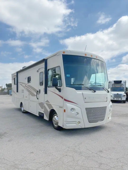 This large Winnebago RV rental is parked on an asphalt lot under a cloudy sky, ready for its next adventure.. Winnebago Vista 2017