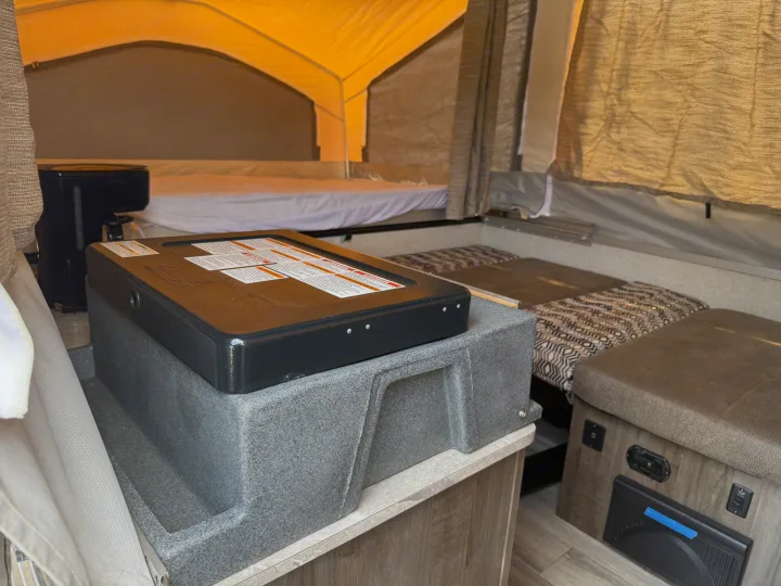Inside a cozy rv rental pop-up camper with beds, a coffee maker, and a portable stove on a counter.. Forest River Flagstaff M.A.C. 2022