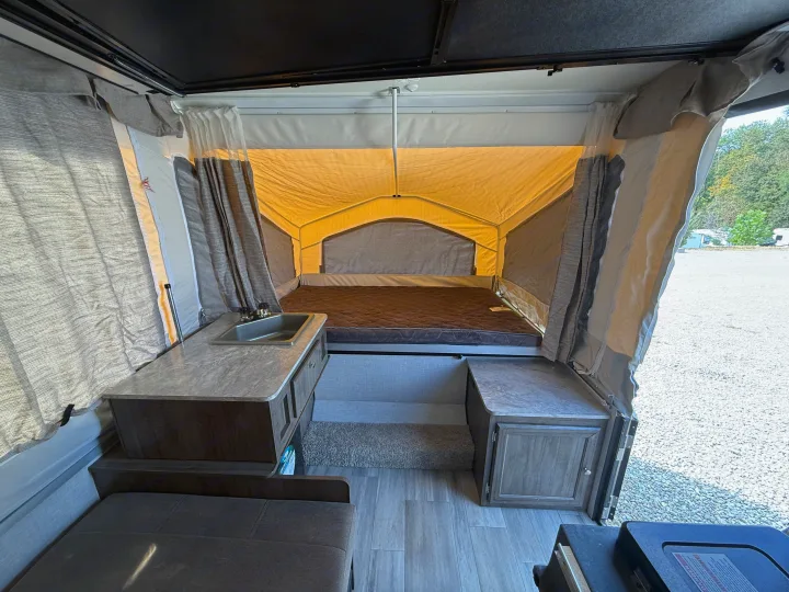Cozy pop-up camper interior, perfect for an RV rental adventure. Features a compact bed and kitchen area.. Forest River Flagstaff M.A.C. 2022