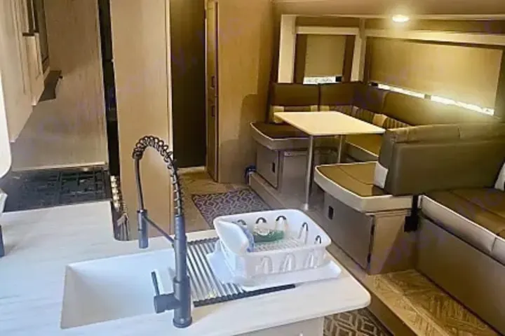 Spacious rv rental interior featuring a modern kitchen with sink and a comfortable dinette seating area for dining.. Salem Cruise LIte Platinum 28VBLX 2024