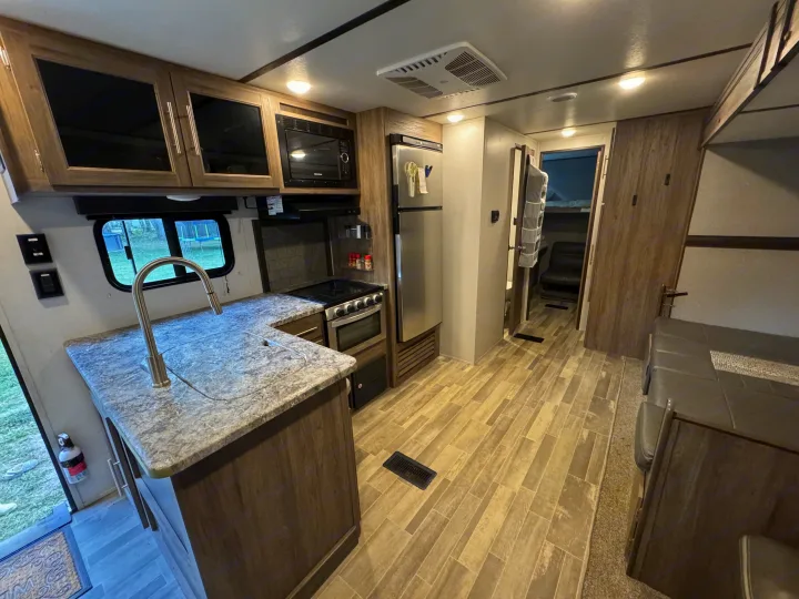 Bright rv rental interior featuring a modern kitchen with granite-look counters, stainless appliances, and comfortable living space.. Crossroads RV Zinger 2020
