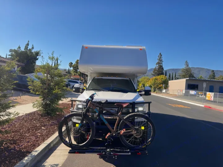 RV rental with a mountain bike on the front rack, ready for outdoor adventures. Clear sky, mountains in the distance.. Ford F350 Diesel Double Cab 2017