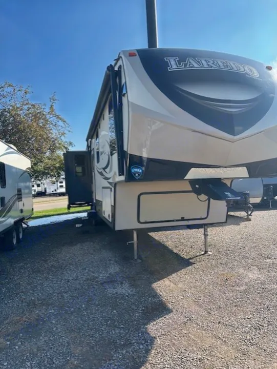 Laredo fifth-wheel RV rental. This spacious travel trailer is parked on a gravel lot under a clear blue sky.. Keystone RV Laredo 2018