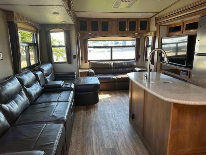 Spacious RV rental interior: modern living area with leather couches, kitchen island, and large windows.. Keystone RV Laredo 2018
