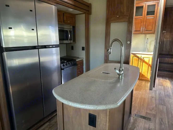 Spacious and modern RV rental kitchen with stainless steel appliances, island, and sink, ready for your next adventure!. Keystone RV Laredo 2018