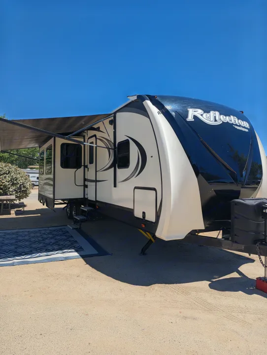 This Grand Design Reflection RV rental is set up at a sunny campsite with its awning extended and an outdoor mat.. Grand Design Reflection 2019
