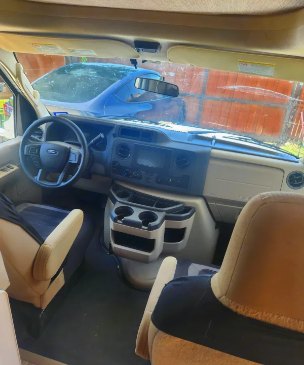 Spacious RV rental cockpit featuring a Ford dashboard, steering wheel, and front seating area. Ready for your adventure.. Thor freedom elite 2022