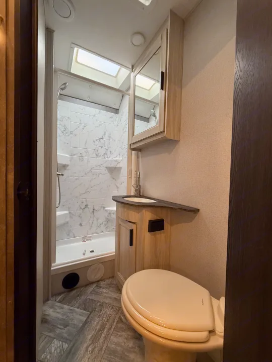 Step inside this RV rental bathroom with a spacious shower, modern vanity, toilet, and natural light from skylights.. Forest River Sunseeker LE 2022