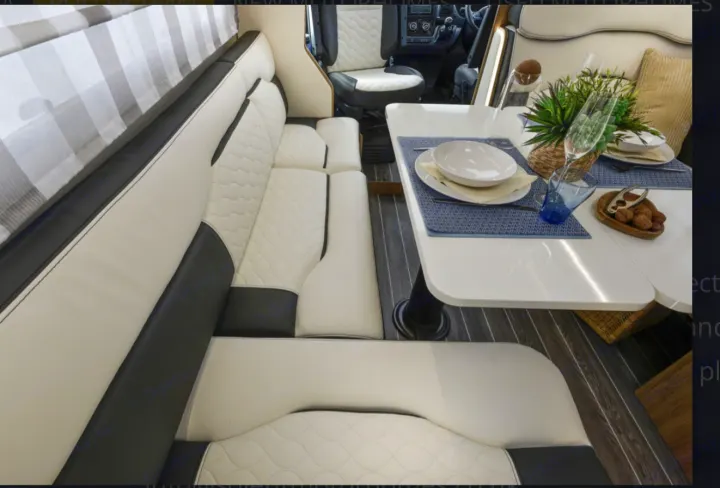 RV rental interior: Modern dining and seating area with two-tone upholstery, a set table, and wood-look flooring.. Roller Team 707 Auto Roller 2025