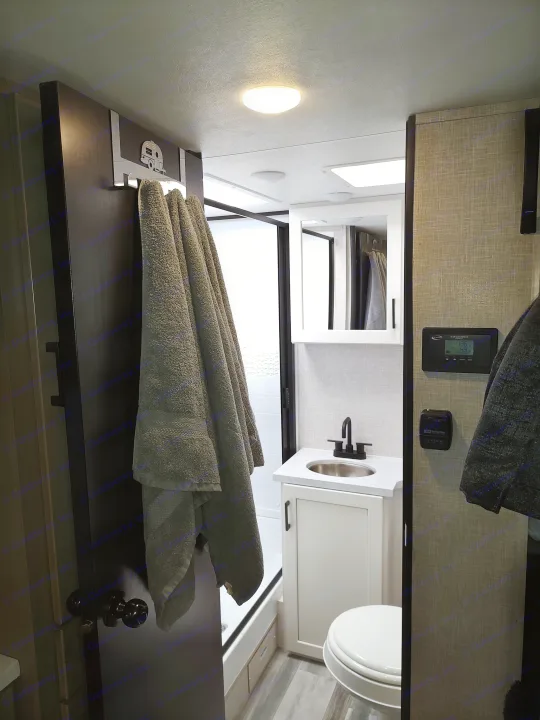 Compact RV rental bathroom: modern vanity, toilet, shower, plus solar controller & thermostat on wall.. Jayco Jay Feather Air 18mbh 2024
