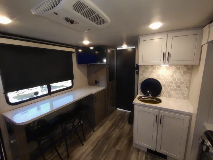 Explore this modern RV rental! Features a compact kitchenette, dining bar, mounted TV, and sleek interior design.. Jayco Jay Feather Air 18mbh 2024