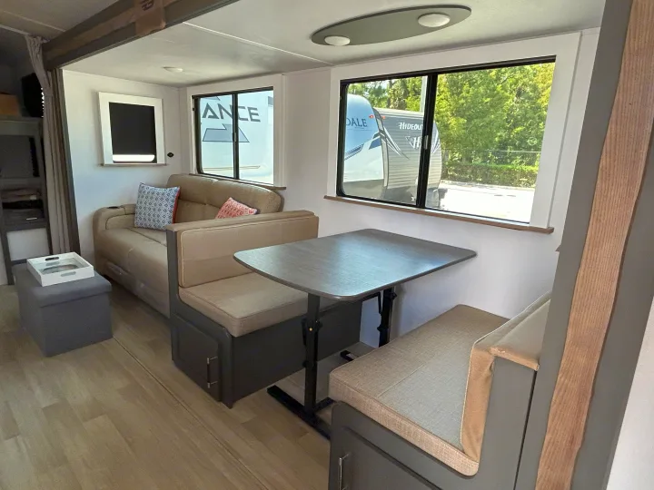 Bright RV rental interior featuring a dinette with bench seating, a comfy sofa, and large windows.. Keystone RV Bullet Crossfire 2025