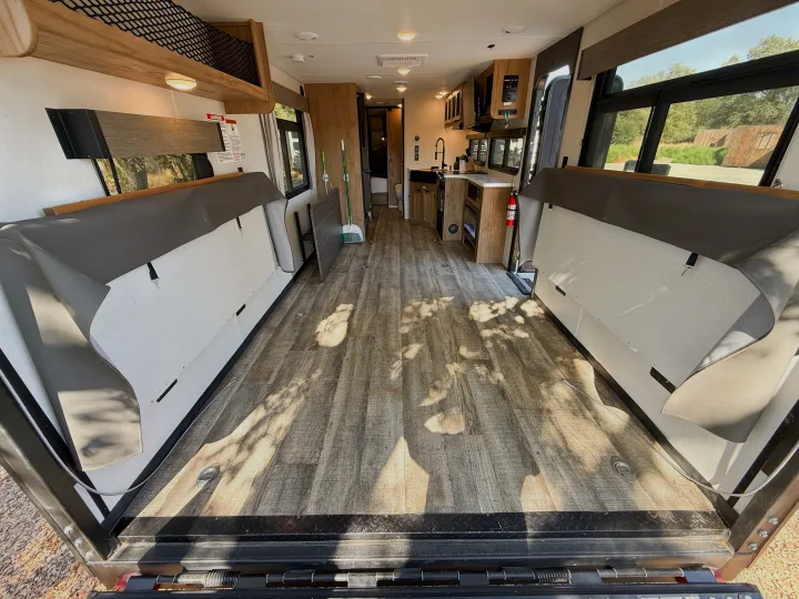 Spacious rv rental toy hauler interior: kitchen, wood-look floor, and versatile seating, ready for adventure.. Forest River Black Label 2024