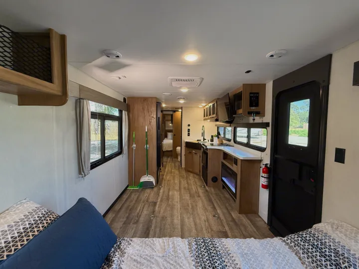 Spacious RV rental interior from the bed, showing a modern kitchen, living area, and rear bedroom. Ready for adventures.. Forest River Black Label 2024