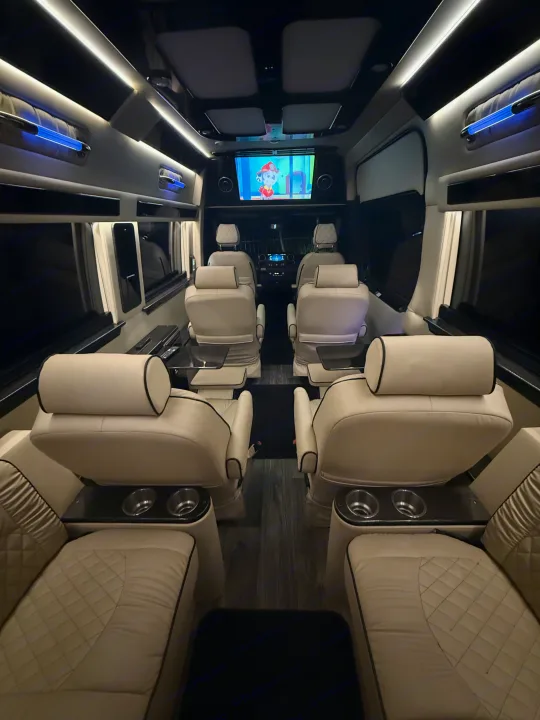 Plush rv rental interior with cream leather seats, entertainment screen, and blue accent lighting for luxury travel.. Ultimate Toys Ultimate Coach 2023