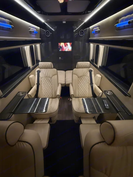 Experience premium comfort in this luxury RV rental, featuring cream quilted seats, personal tables, a TV, and ambient lighting.. Ultimate Toys Ultimate Coach 2023