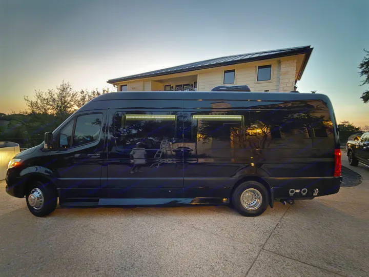 Luxury black Sprinter van with custom interior lighting, ideal for an rv rental or glamping adventure at dusk.. Ultimate Toys Ultimate Coach 2023