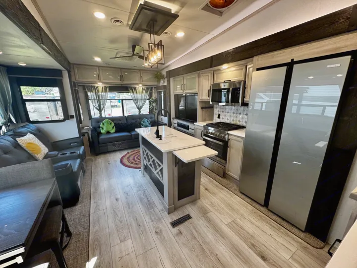 Bright, modern rv rental interior with a kitchen island, full appliances, and a comfortable living area with recliners.. Keystone RV Montana High Country 2024