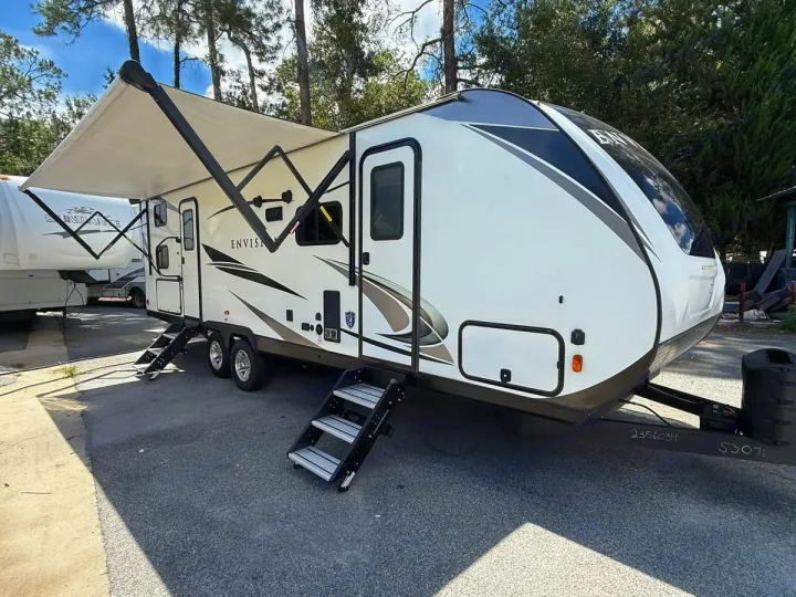 This Envision travel trailer RV rental, featuring a deployed awning and convenient steps, is ready for your adventure.. Gulf Stream Envision 2023