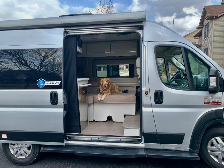 Happy golden retriever enjoying the spacious interior of an open RV rental camper van, ready for adventure.. Thor Rize 2022
