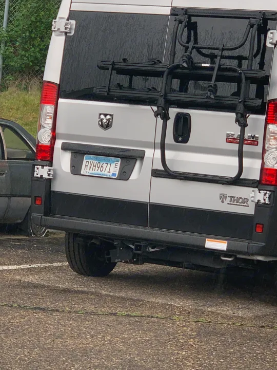 Rear view of a silver Thor Ram ProMaster RV rental van with a Thule bike rack and Minnesota "Recreational Vehicle" plate RVH9671.. Thor Rize 2022