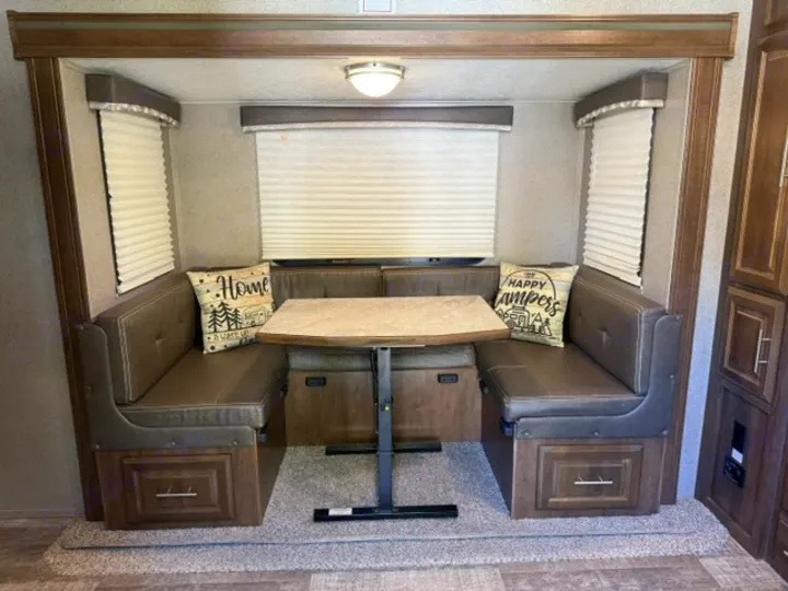 Cozy RV rental dinette with comfortable booth seating, a central table, and decorative pillows in a camper's interior.. Forest River Rockwood Mini Lite 2020