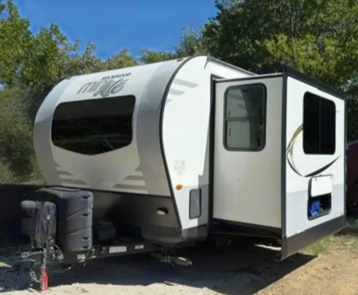 White and grey travel trailer RV rental parked outdoors, slide-out extended. Perfect for your next adventure.. Forest River Rockwood Mini Lite 2020