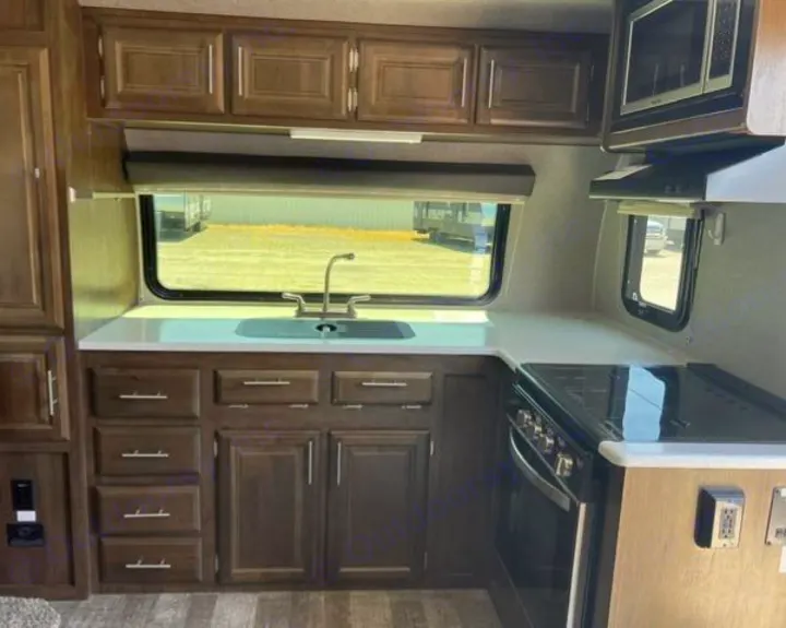 RV rental kitchen: Dark wood cabinets, white counters, a sink, gas stove, and microwave. Ready for your road trip!. Forest River Rockwood Mini Lite 2020