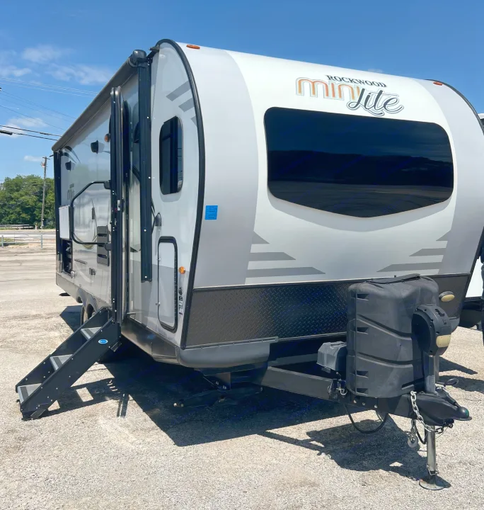 Light grey Rockwood Mini Lite travel trailer RV rental, steps extended on gravel, ready for your next camping adventure.. Forest River Rockwood Mini Lite 2020