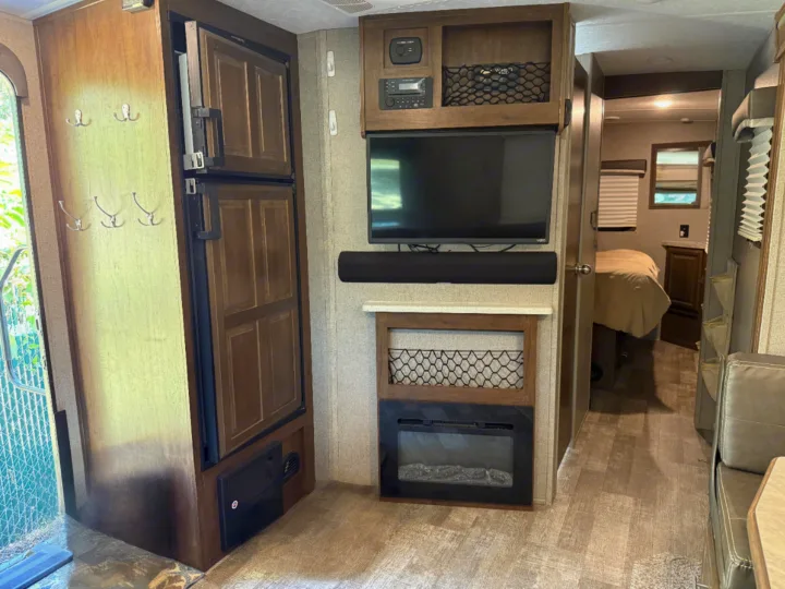 This rv rental's cozy interior features a full fridge, TV, electric fireplace, and bedroom access, ideal for comfortable travel.. Forest River Rockwood Mini Lite 2020