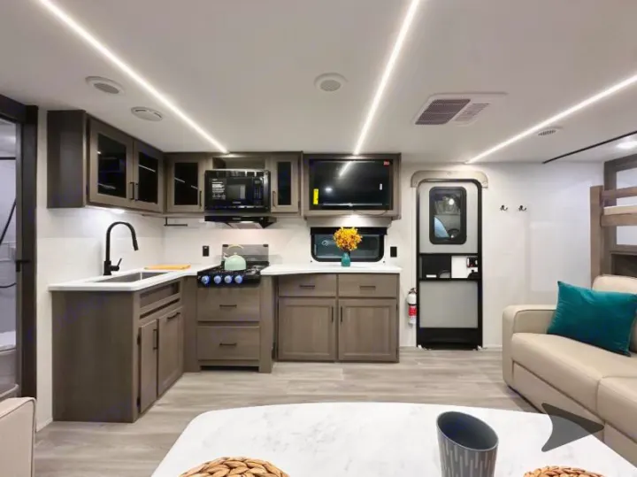 Modern RV rental interior showing a well-equipped kitchen, cozy living area, and bunks for family adventures.. Grand Design Transcend 2026