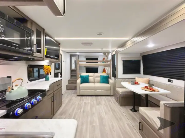 This spacious RV rental interior features a modern kitchen, dinette, cozy sofa, and convenient bunk beds, perfect for family adventures.. Grand Design Transcend 2026