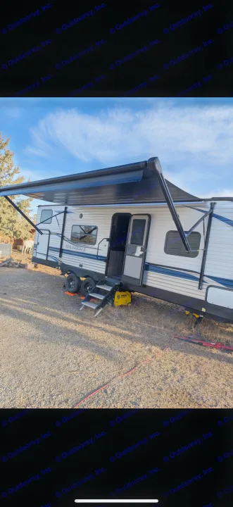 Springdale RV rental with extended awning, steps, and generator, parked under blue skies. A horse is in the background.. Keystone RV Springdale 2022