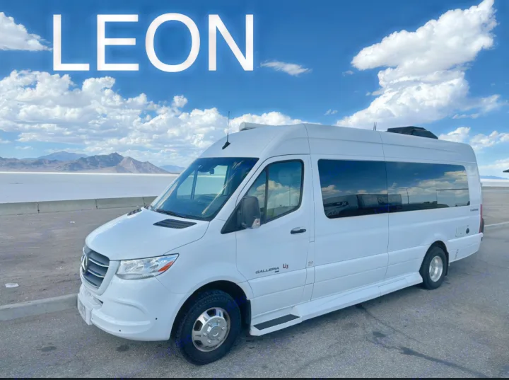"LEON," a white Mercedes Sprinter Class B RV rental, parked by salt flats with mountains under cloudy skies.. Coachmen Galleria 2021