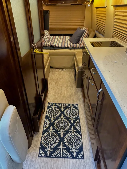 RV rental interior featuring a cozy living area, modern kitchen counter, and central aisle with a dark patterned rug.. Coachmen Galleria 2020