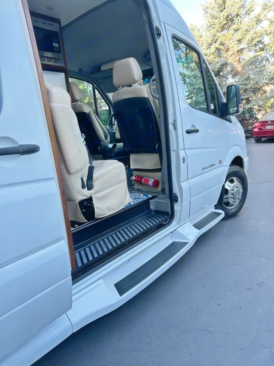 White Mercedes Sprinter RV rental with open door showing luxury interior, steps, and microwave.. Coachmen Galleria 2020