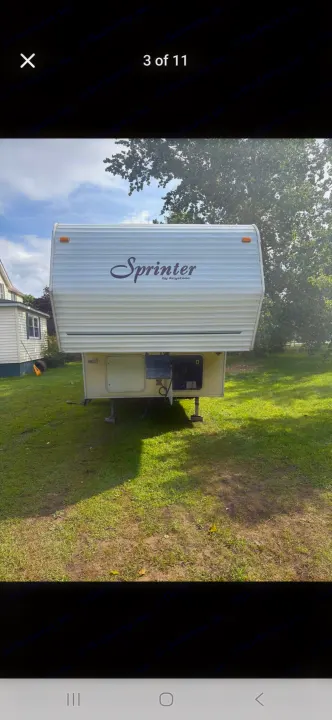 Front view of a white Sprinter by Keystone fifth-wheel RV parked on grass. Great for your next rv rental or camping trip!. Keystone RV Sprinter 2000