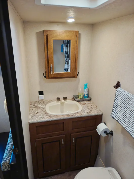 This RV rental bathroom features a compact vanity with a sink, mirror, toilet, and towel, designed for small travel spaces.. Forest River Salem FSX 2018