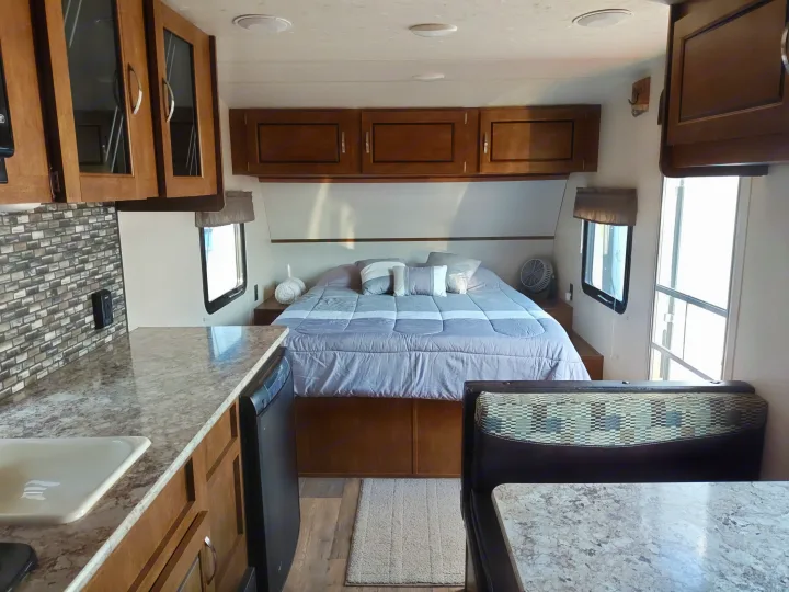 Inside this comfy RV rental: a neat bedroom, well-equipped kitchen with counter & sink, plus a dining booth.. Forest River Salem FSX 2018