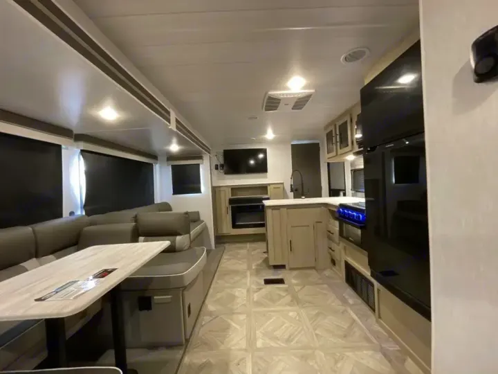 Bright, modern RV rental interior featuring a full kitchen, comfortable L-shaped dinette, and entertainment area.. Forest River Salem Platinum 2024