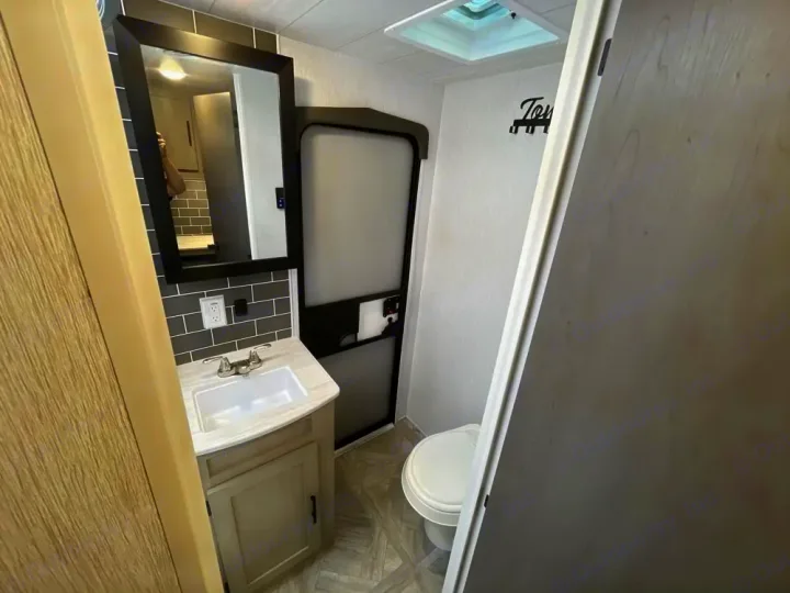 RV rental bathroom features a sink, mirror, and toilet, with a compact design for travel convenience.. Forest River Salem Platinum 2024