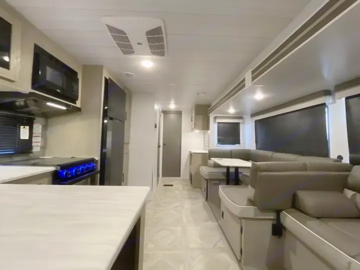 Spacious RV rental interior featuring a modern kitchen with blue-lit stovetop, dining booth, and comfortable living area.. Forest River Salem Platinum 2024