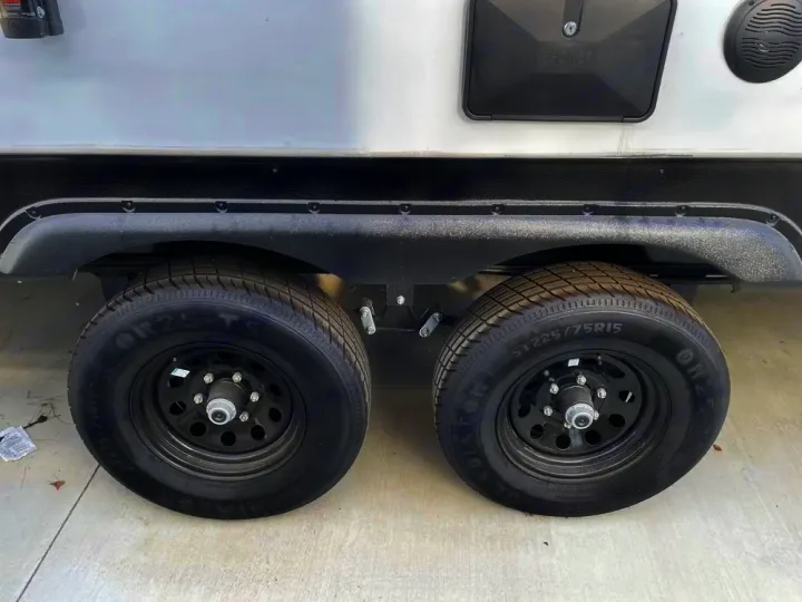 Close-up of the dual axle ST225/75R15 tires on an RV rental, showing black rims and fender.. Forest River Salem Platinum 2024
