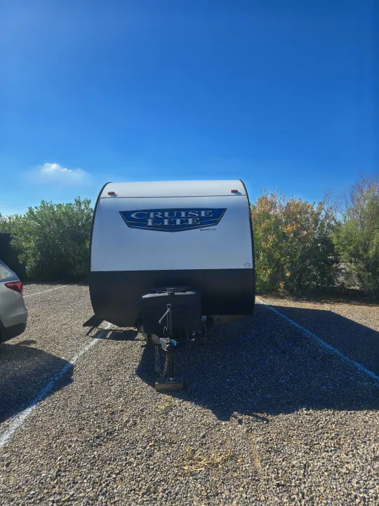 Front view of a white 'Cruise Lite' RV rental parked on gravel. Perfect for camping under the clear blue sky!. Forest River Salem Cruise Lite 2024