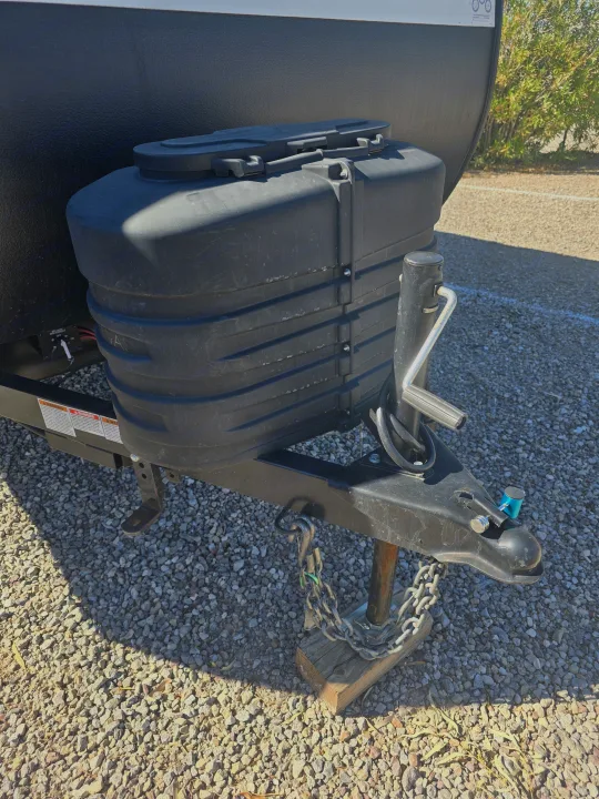 RV rental trailer hitch area, featuring black propane cover, jack, safety chains, and coupler on gravel.. Forest River Salem Cruise Lite 2024