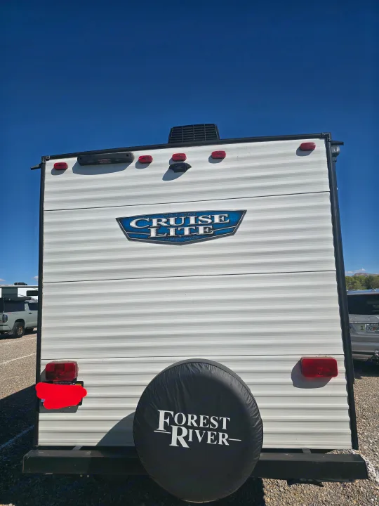 Explore this white Forest River Cruise Lite RV rental from the rear, featuring a spare tire cover and blue sky, ready for your next camping adventure.. Forest River Salem Cruise Lite 2024
