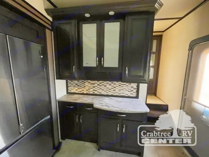 Explore this RV rental's sleek kitchen: stainless fridge, dark cabinets, patterned backsplash, and spacious counter.. Grand Design Momentum 2015