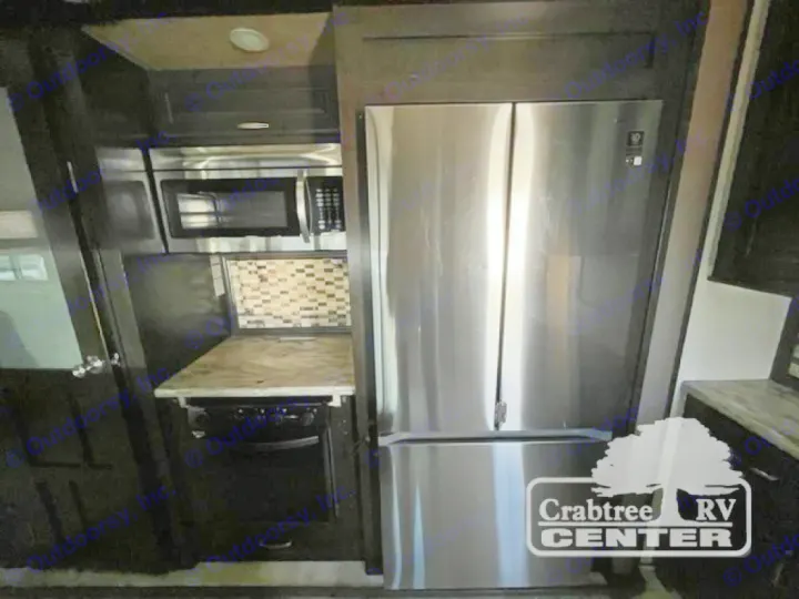 Well-equipped RV rental kitchen: stainless steel fridge, microwave, stove, and stylish backsplash for your travels.. Grand Design Momentum 2015